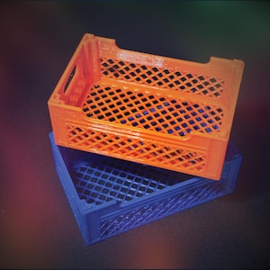 Puede incluir: Dos cajas de plástico apiladas una encima de la otra. La caja superior es naranja y la caja inferior es azul. Ambas cajas tienen un patrón de cuadrícula.