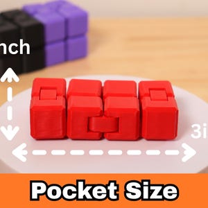 May include: A red fidget toy, approximately 3 inches long and 1 inch wide, is displayed on a white surface. The text "Pocket Size" is visible at the bottom. Other colorful fidget toys are in the background.