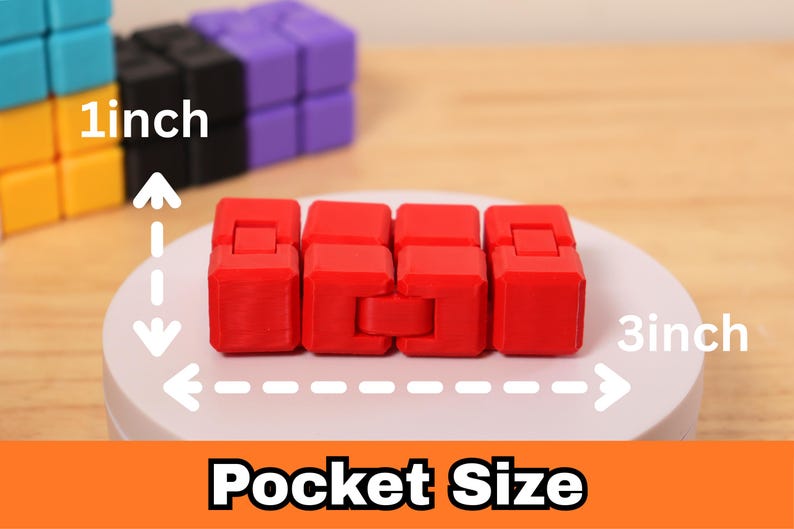 May include: A red fidget toy, approximately 3 inches long and 1 inch wide, is displayed on a white surface. The text "Pocket Size" is visible at the bottom. Other colorful fidget toys are in the background.