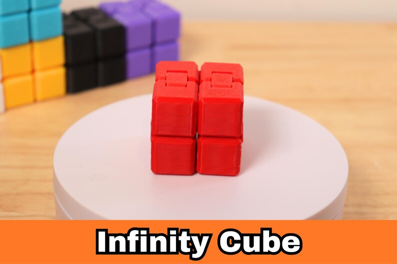 May include: A red Infinity Cube is displayed on a white platform, with other colorful cubes in the background. The cube is made of eight connected blocks that can be manipulated. The text "Infinity Cube" is displayed in a banner below.