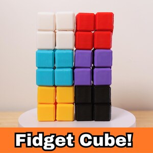 May include: A colorful fidget cube composed of sixteen small, square blocks. The blocks are arranged in four rows of four, with each row a different color: white, red, turquoise, purple, yellow, and black. The text "Fidget Cube!" is displayed at the bottom.