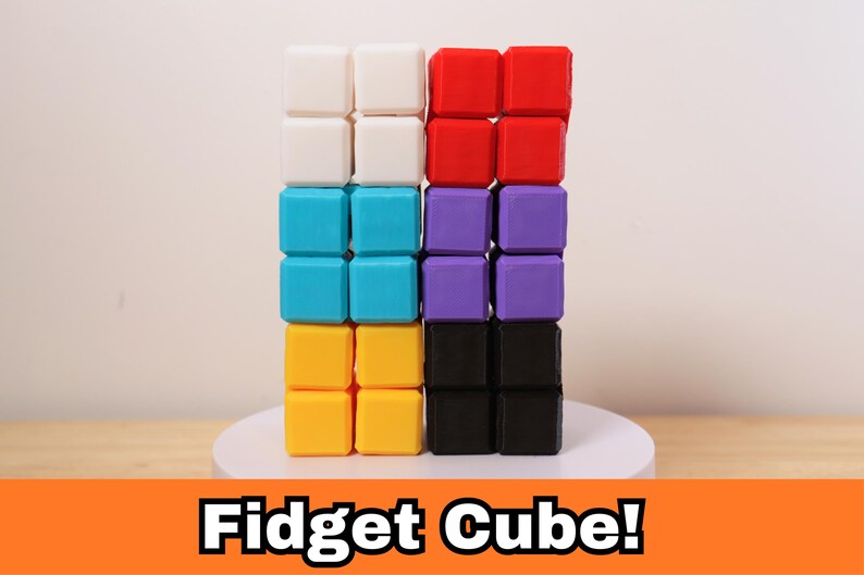 May include: A colorful fidget cube composed of sixteen small, square blocks. The blocks are arranged in four rows of four, with each row a different color: white, red, turquoise, purple, yellow, and black. The text "Fidget Cube!" is displayed at the bottom.
