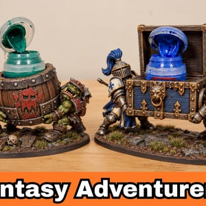 May include: Two miniature dioramas featuring fantasy figures. On the left, two green orcs carry a brown wooden barrel containing a green paint pot. On the right, two knights in blue and white armor carry a blue treasure chest holding a blue paint pot.
