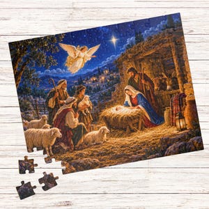 Könnte beinhalten: Ein Puzzle, das eine Krippenszene mit einer zentralen Krippe, Figuren in Gewändern, Schafen und einem leuchtenden Engel am sternenklaren Nachthimmel zeigt. Die Puzzleteile liegen verstreut am unteren Rand und zeigen eine blau-goldene Farbpalette.