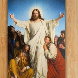Op de afbeelding: Een legpuzzel van 1014 stukjes met een religieus schilderij van een centrale figuur in een wit gewaad met uitgestrekte armen, omringd door verschillende mensen in gewaden van diverse kleuren tegen een blauwe lucht. De tekst 1014 Piece Jigsaw Puzzle is zichtbaar.