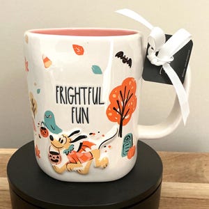 以下が含まれることがあります： ピンク色の内側を持つ白いセラミックマグ。ハロウィーンをテーマにしたデザインです。マグには、漫画の犬、幽霊、秋の葉のイラストが描かれています。「FRIGHTFUL FUN」の文字が表示されています。白いリボンとタグがハンドルに付いています。