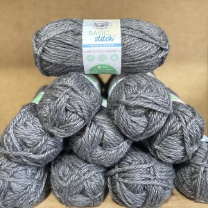May include: A stack of grey yarn balls labelled "Basic Stitch Thick & Quick...anti-microbial..."