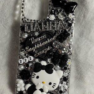 May include: A black and white Hello Kitty phone case with rhinestones, a black bow, and the text "Taurus Sagittarius Scorpio" and "222".