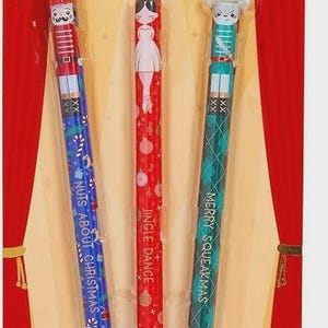 May include: A pack of three erasable gel pens with a "Nutcracker" theme. The pens have blue, red, and green ink and feature festive designs. Each pen has a different design, including a nutcracker, a ballerina, and a mouse king. The pens are 0.7 mm.
