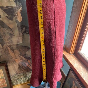 May include: A burgundy skirt with a textured pattern and a zipper closure. The skirt is approximately 23 inches long.