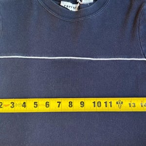 K&ouml;nnte beinhalten: Marineblaues Kurzarm-Shirt mit einem wei&szlig;en horizontalen Streifen &uuml;ber der Brust. Das Shirt hat blau-wei&szlig;e Streifen auf den &Auml;rmeln. Das Shirt misst ca. 38 cm &uuml;ber der Brust.