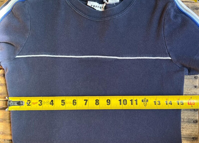 K&ouml;nnte beinhalten: Marineblaues Kurzarm-Shirt mit einem wei&szlig;en horizontalen Streifen &uuml;ber der Brust. Das Shirt hat blau-wei&szlig;e Streifen auf den &Auml;rmeln. Das Shirt misst ca. 38 cm &uuml;ber der Brust.