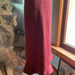 May include: A burgundy midi skirt with a textured pattern and a flared hem.