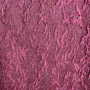 May include: Close-up of a deep burgundy fabric with a textured, woven pattern. The fabric has a subtle shimmer.