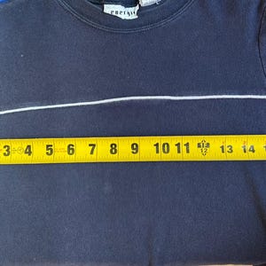 K&ouml;nnte beinhalten: Marineblaues Sweatshirt mit Rundhalsausschnitt und einem wei&szlig;en horizontalen Streifen &uuml;ber der Brust. Die &Auml;rmel haben blaue Streifen. Das Ma&szlig;band zeigt, dass das Hemd etwa 40 cm breit ist. Das Etikett lautet "energy".