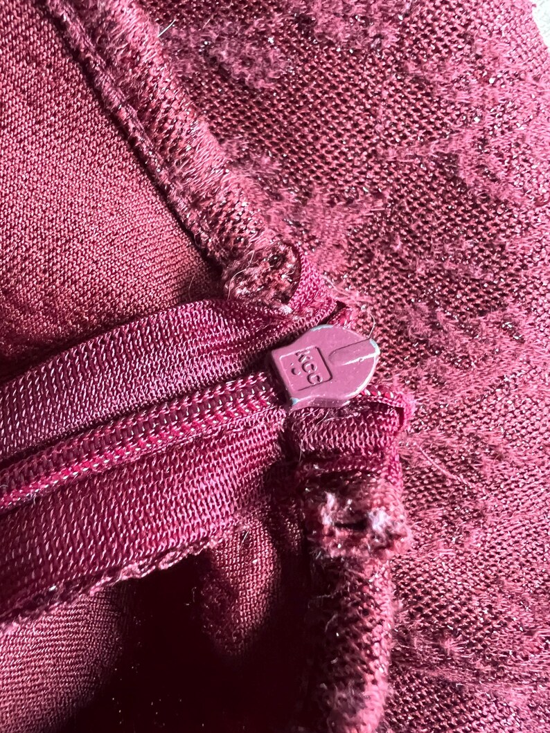 May include: Close-up of a maroon zipper with a plastic zipper pull. The zipper pull has the number "400" printed on it.