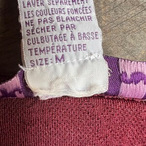 May include: White care label with instructions for washing and drying a garment in French. The label reads "LAVER &Agrave; LA MACHINE &Agrave; L'EAU FROIDE LAVER S&Eacute;PAR&Eacute;MENT LES COULEURS FONC&Eacute;ES NE PAS BLANCHIR S&Eacute;CHER PAR CULBUTAGE &Agrave; BASSE TEMP&Eacute;RATURE SIZE: M".