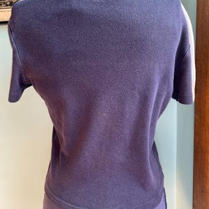 K&ouml;nnte beinhalten: Ein marineblaues Kurzarmshirt mit wei&szlig;en Streifen auf den &Auml;rmeln. Das Shirt wird auf einer Schaufensterpuppe pr&auml;sentiert. Der Stoff scheint ein weiches Strickmaterial zu sein. Das Shirt hat einen Rundhalsausschnitt.