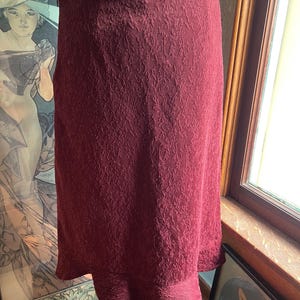 May include: A burgundy skirt with a textured pattern and a ruffled hem.