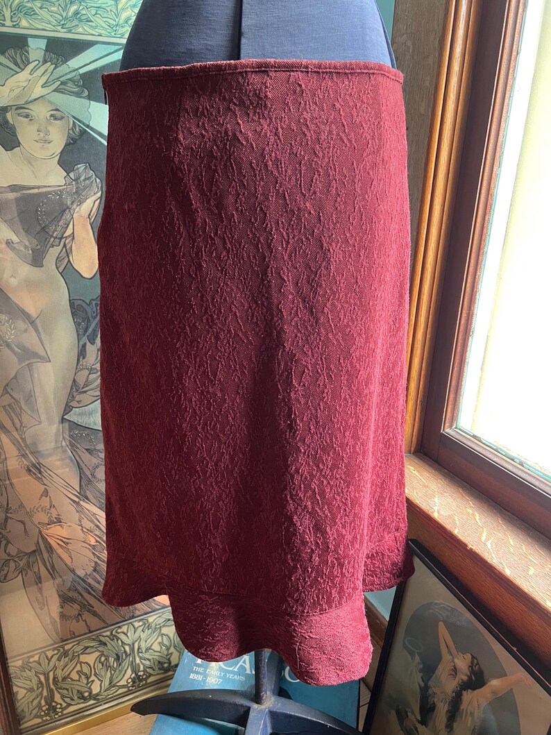 May include: A burgundy skirt with a textured pattern and a ruffled hem.
