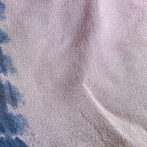 Peut inclure: Gros plan sur un tissu rose clair et transparent &agrave; la texture subtile. Le tissu a un l&eacute;ger &eacute;clat et semble l&eacute;ger. De faibles motifs floraux bleus et roses sont visibles dans le coin du tissu.