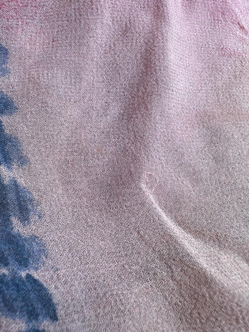 Peut inclure: Gros plan sur un tissu rose clair et transparent &agrave; la texture subtile. Le tissu a un l&eacute;ger &eacute;clat et semble l&eacute;ger. De faibles motifs floraux bleus et roses sont visibles dans le coin du tissu.
