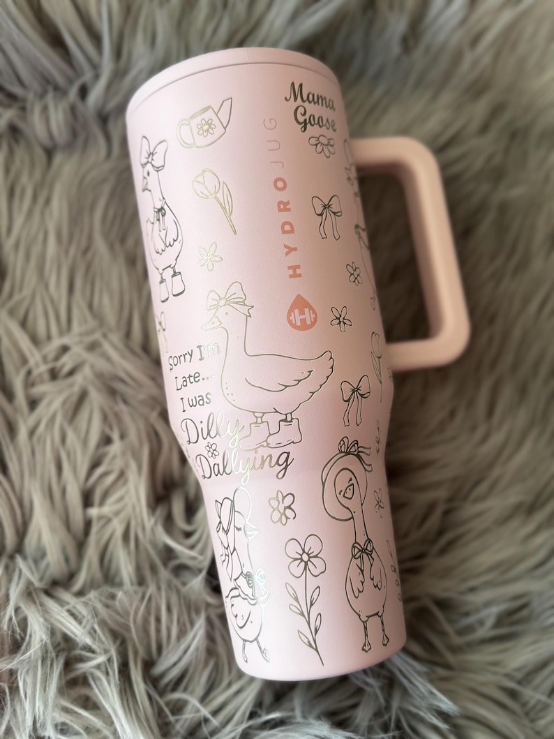 May include: A pink HydroJug water bottle with a handle, featuring a Mama Goose design. The bottle is adorned with illustrations of geese, bows, flowers, and the text "Sorry I'm Late... I was Dilly Dallying."