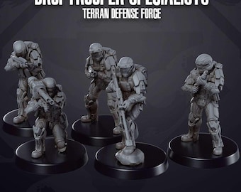 Puede incluir: Un grupo de cinco figuras en miniatura grises de soldados con armadura futurista, cada una posando con armas sobre bases circulares negras. El texto "DROPTROOPER SPECIALISTS" y "TERRAN DEFENSE FORCE" se muestra encima de las figuras.
