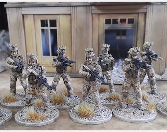 Könnte beinhalten: Eine Gruppe von 10 Militärfiguren in Wüsten-Tarnuniformen, die Gewehre halten. Die Figuren sind in verschiedenen Posen dargestellt und stehen auf kleinen runden Sockeln.