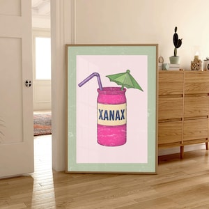 Könnte beinhalten: Gerahmter Kunstdruck mit einer rosa Dose mit dem Wort "XANAX" auf einem gelben Etikett. Ein lila Strohhalm und ein grüner Schirm sind oben platziert. Das Kunstwerk hat einen Vintage-Look.