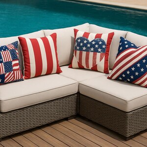 May include: A corner sofa with beige cushions and a brown woven frame. The sofa is decorated with cushions in red, white, and blue, featuring stripes, stars, and flag patterns. The sofa is near a swimming pool.