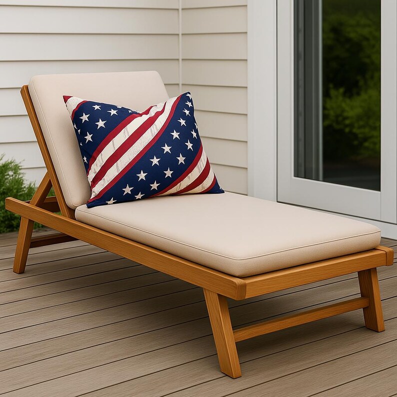 May include: A wooden sun lounger with a beige cushion and a decorative pillow. The pillow has a patriotic design with red and white stripes and blue with white stars. The lounger is on a wooden deck.