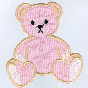 Op de afbeelding: Applicatie van een teddybeer in roze en witte gingham met een gouden rand. De beer zit met gekruiste benen en heeft een wit gezicht met zwarte ogen en een zwarte neus.