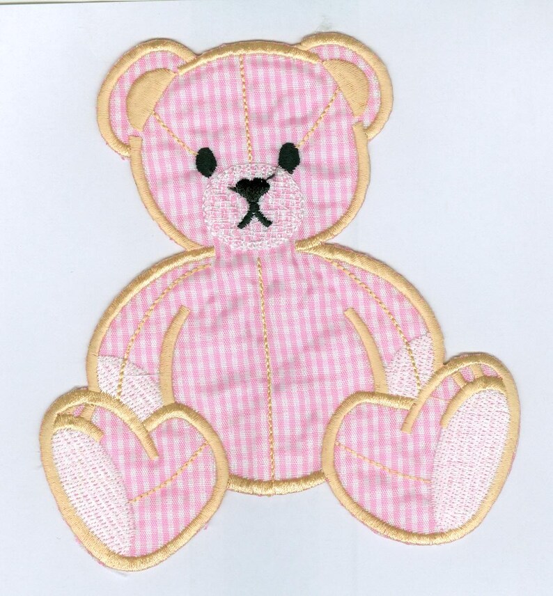 Op de afbeelding: Applicatie van een teddybeer in roze en witte gingham met een gouden rand. De beer zit met gekruiste benen en heeft een wit gezicht met zwarte ogen en een zwarte neus.