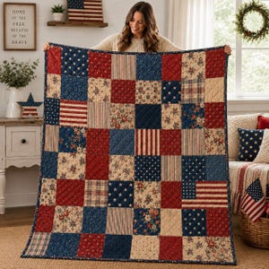 May include: A rectangular patchwork quilt featuring a grid of squares in red, white, and blue. The fabric patterns include stars, stripes, and floral prints. The quilt has a dark blue border and visible diagonal stitching throughout the surface.