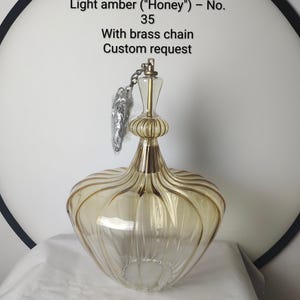May include: A light amber glass pendant lamp with a brass chain. The lamp is 14 inches in height and has a unique, ribbed design. The text on the image reads: Custom order - 14 inches Light amber ("Honey") - No. 35 With brass chain Custom request.