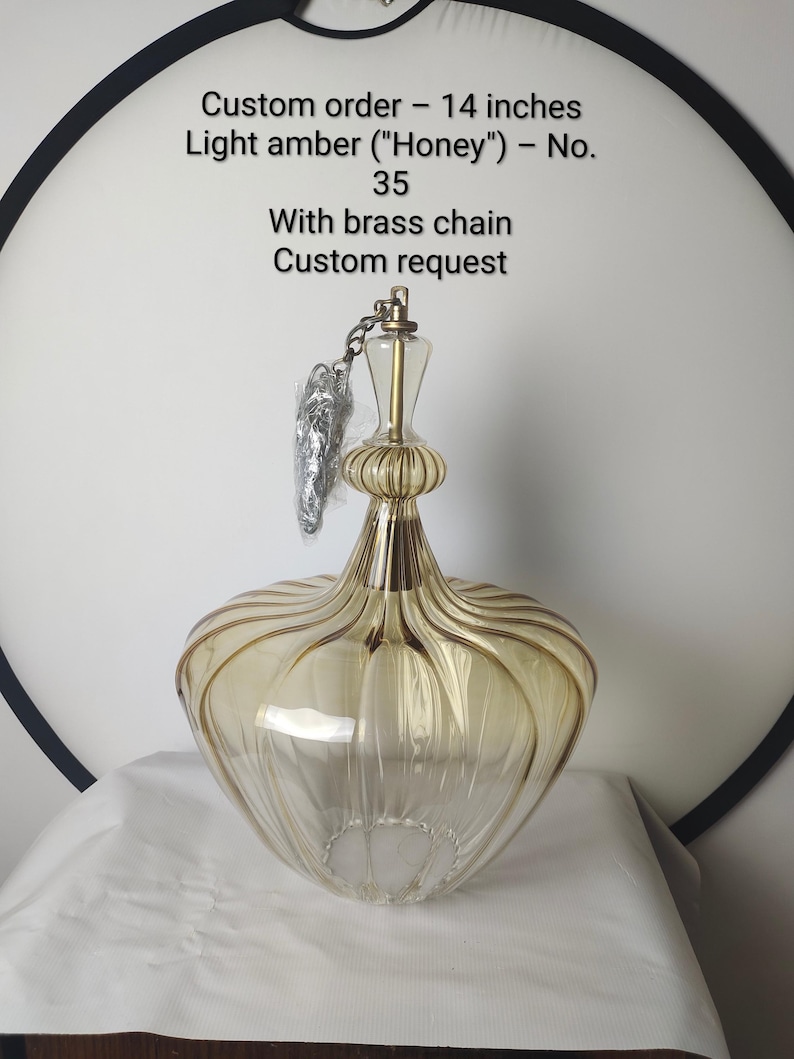 May include: A light amber glass pendant lamp with a brass chain. The lamp is 14 inches in height and has a unique, ribbed design. The text on the image reads: Custom order - 14 inches Light amber ("Honey") - No. 35 With brass chain Custom request.