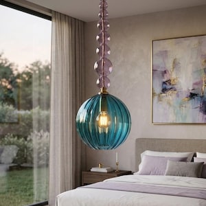 May include: A pendant light featuring a large, ribbed, teal-colored glass globe shade suspended by a vertical stem composed of stacked, translucent purple glass spheres. The fixture includes a gold-toned ceiling mount and a single exposed light bulb.