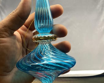 Puede incluir: Adorno de vidrio soplado a mano con un diseño de remolino azul y blanco. El adorno tiene forma de lágrima con un acento metálico dorado y una parte superior de vidrio transparente. Se adjunta una cuerda dorada para colgar. Mide aproximadamente 15 cm de largo.