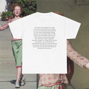 May include: White t-shirt with a quote about the magic of going to the movies. The quote reads: "We come to this place for magic. We come to AMC theaters to laugh, to cry, to care because we need that all of us that indescribable feeling we get when the lights begin to dim and we go somewhere we've never been before, not just entertained but somehow reborn together. Dazzling images on a huge silver screen, sound that I can feel somehow, heartbreak feels good in a place like this, our heroes feel like the best part of us and stories feel perfect and powerful because here they are."