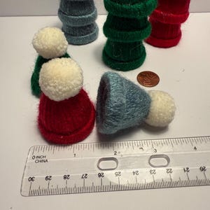 May include: A set of six felt Christmas tree ornaments. The ornaments are in the shape of Christmas trees and are made of felt. The trees are in three colors: red, green, and blue. The ornaments are about 3 inches tall.