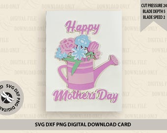 Puede incluir: Una tarjeta blanca con el texto "Happy Mothers Day" en letras rosas y doradas. Una regadera rosa con un arreglo floral rosa, azul y verde se encuentra en el centro de la tarjeta.