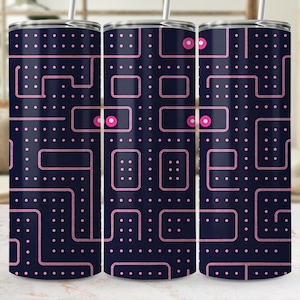 May include: A cylindrical stainless steel tumbler with a dark navy blue background featuring a repeating pink maze pattern inspired by retro arcade games. The design includes small pink dots and circular pink power pellets, topped with a silver lid and straw.