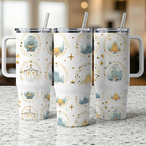 May include: Three white travel mugs with a repeating pattern of celestial illustrations in gold, blue, and yellow. Each mug has a silver straw, a white handle, and a black lid. The mugs are on a light-colored surface.