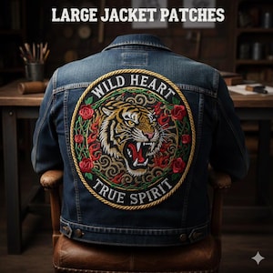 Puede incluir: Chaqueta vaquera azul oscuro con un parche bordado grande. El parche muestra un tigre rodeado de rosas rojas y hojas verdes. Las palabras "WILD HEART" y "TRUE SPIRIT" también están presentes.