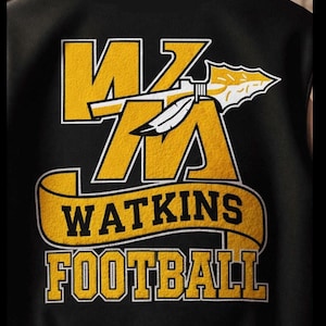 Puede incluir: Chaqueta universitaria negra con letras doradas y blancas. La parte trasera de la chaqueta presenta el texto "MZ WATKINS FOOTBALL" en un estilo universitario audaz. También se incluye una pluma y una punta de flecha decorativas.