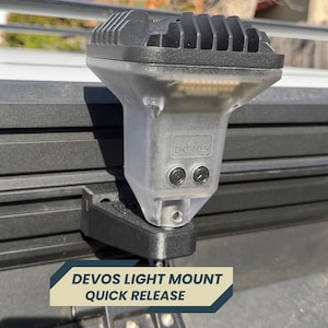 May include: A black and clear light mount attached to a vehicle. The light has a ridged top and the text "devos" is visible. The mount is labeled "DEVOS LIGHT MOUNT QUICK RELEASE".
