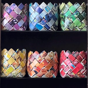 May include: Nine woven magazine baskets in various colors and patterns. The baskets are arranged in three rows of three. The baskets are made from recycled magazines and are a great way to add a touch of color and style to your home.