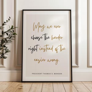 May include: Framed print with a black border featuring a quote in gold and black script: "May we ever choose the harder right instead of the easier wrong." The author is President Thomas S. Monson. The print is displayed on a light background.
