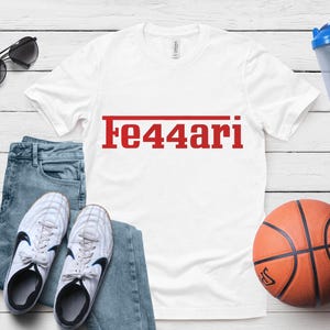 May include: White t-shirt with the red text "Fe44ari" above a red line. The shirt is next to blue jeans, white sneakers, a basketball, sunglasses, and a blue water bottle.